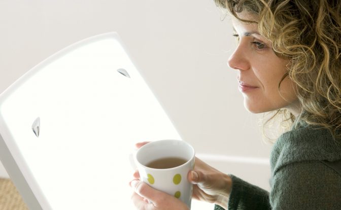 Eine Frau sitzt vor einer Tageslichtlampe